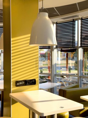 Téléchargez les photos : Kehl, Allemagne - 29 sept. 2023 : Un restaurant McDonalds vide tôt le matin, présentant des tables de bar équipées de prises de courant pour les dispositifs de charge. - en image libre de droit