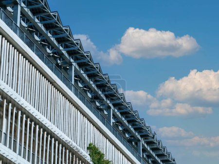 Foto de Las baterías solares se instalan de manera prominente en la azotea de una moderna estructura de estacionamiento, enmarcada por un telón de fondo de un cielo azul vívidamente claro. - Imagen libre de derechos