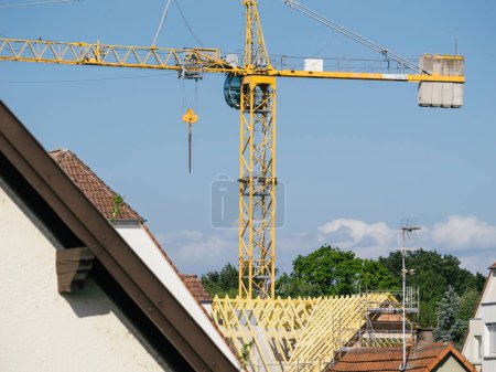 Photo for Captured through a telephoto lens, a panorama of rooftops unfolds, punctuated by a towering crane actively involved in one buildings construction. - Royalty Free Image