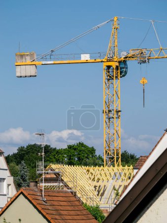 Téléchargez les photos : La touche finale d'une nouvelle maison est rendue possible grâce aux efforts incessants d'une grande grue jaune sur la scène de la construction sur le toit - en image libre de droit