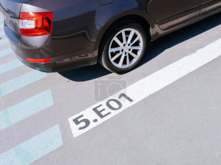 Photo for A car is impeccably parked adjacent to a white line marked with the number 5.E01, showcasing an example of public parking and eco-friendly transportation. - Royalty Free Image