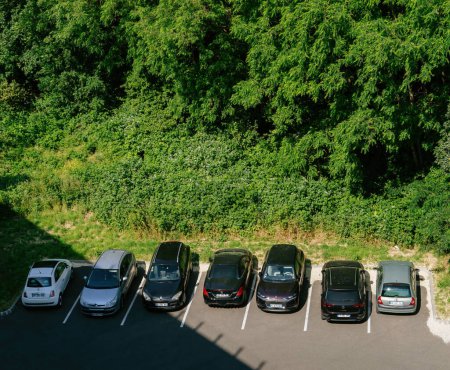 Photo for Strasbourg, France - Jun 5, 2023: Eco-friendly vehicles from multiple brands like Dacia, VW, Citroen, Renault, Mercedes, and Peugeot are precisely parked near a forested area. - Royalty Free Image