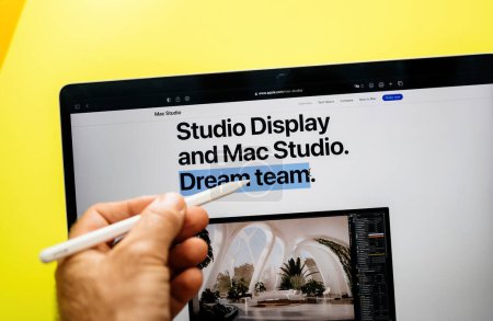 Foto de París, Francia - 6 de junio de 2023: Studio Display y Mac Studio: Un equipo de ensueño - Hombre de la mano con Apple Pencil surfing Sitio web oficial de Apple - Imagen libre de derechos