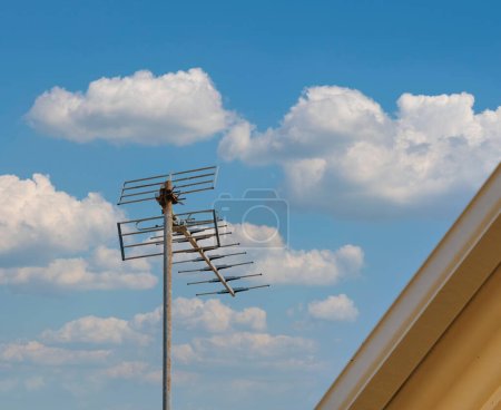 Téléchargez les photos : Une grande antenne aérienne se dresse bien en vue au-dessus d'un bâtiment, sur fond contrasté d'un ciel bleu clair. - en image libre de droit