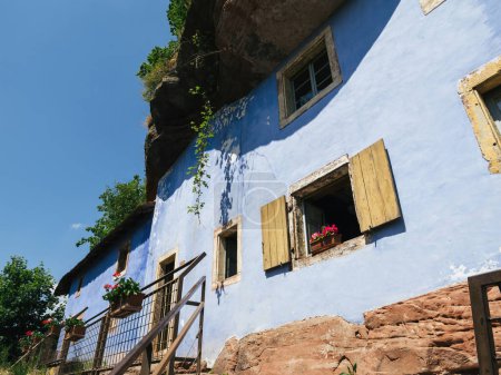 Téléchargez les photos : L'entrée accueillante vous attire vers la façade bleue des maisons troglodytes, élégamment situées à Graufthal, Eschbourg, Bas-Rhin, Alsace, France. - en image libre de droit