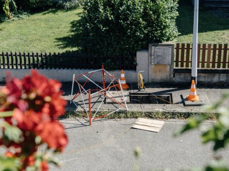 Photo for Urban optical fiber FTTH installation is underway, featuring an open canalization duct in the city sidewalk, complete with protective structures and signaling cones adjacent to the excavation - Royalty Free Image