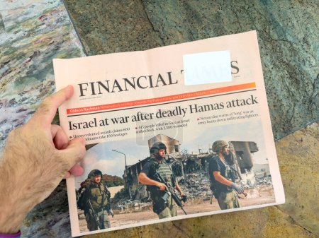 Photo for Paris, France - Oct 9, 2023: POV male hand reading Financial Times edition headline Israel at waar after unprecendent assualt - Gaza - Israel conflict . Palestinian militant groups led by Hamas - Royalty Free Image