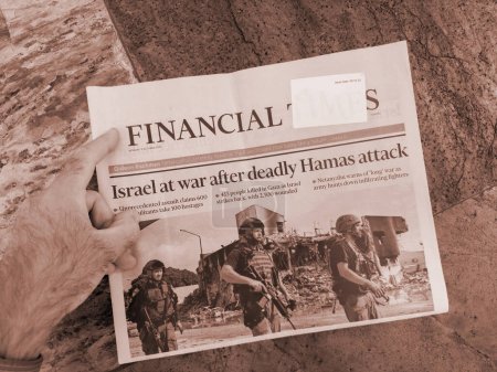 Téléchargez les photos : Paris, France - 9 oct. 2023 : une main masculine est capturée dans le Financial Times, le titre criant Israël à la guerre après une agression sans précédent dans le conflit Gaza-Israël - en image libre de droit