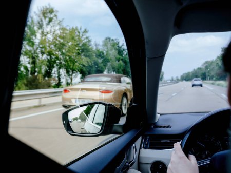 From the drivers POV, attention is directed towards the rearview mirror, underlining the significance of safety and alertness on highways or in urban areas