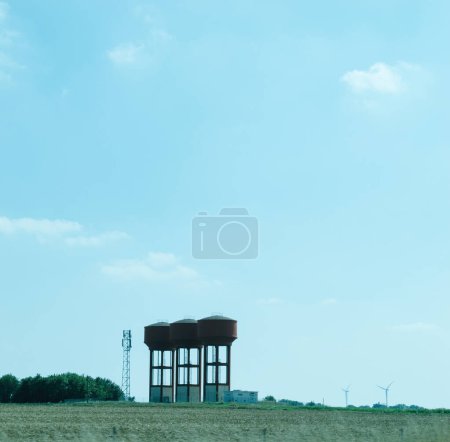 Foto de Torres de agua construidas de forma segura en un entorno rural francés, enmarcadas por un cielo azul vivo, que abogan por prácticas ambientalmente sostenibles. - Imagen libre de derechos