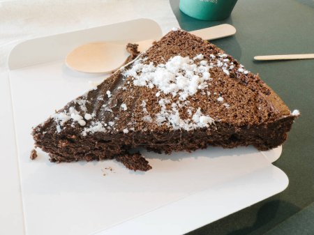 Téléchargez les photos : Délicieux gâteau recouvert de sucre en poudre, présenté sur une table avec une cuillère en bois à proximité. - en image libre de droit