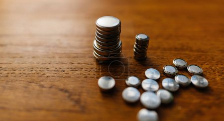 Photo for Button cell batteries arranged in a stack forming a complex cityscape on a wooden table - Royalty Free Image