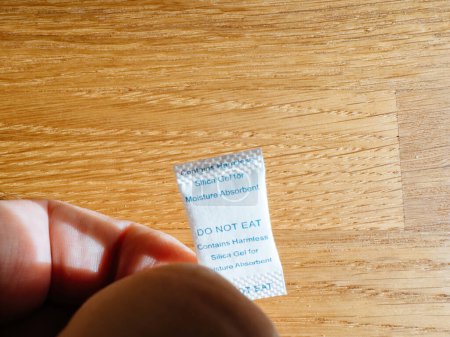 Photo for Male hand holding moisture absorber - silica gel, do not ingest - Royalty Free Image