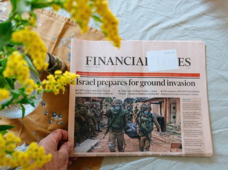 Photo for Paris, France - Oct 11, 2023: Man reading latest Financial Times newspaper with headlines Israel prepares for ground invasion in Gaza - Royalty Free Image