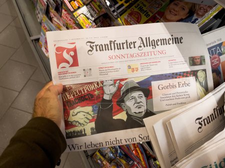 Foto de Frankfurt, Alemania - 3 de septiembre de 2022: Hombre agarrando a mano el periódico Frankfurter Allgemeine, con una portada ilustrativa de Mikhail Gorbachev, adquirida en el supermercado - Imagen libre de derechos