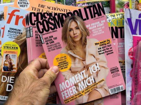 Foto de Frankfurt, Alemania - 17-sep-2022: Hombre que compra a mano Cosmopolitan con Jennifer Aniston en un abrigo ligero en la portada de esta revista reconocida a nivel mundial - Imagen libre de derechos