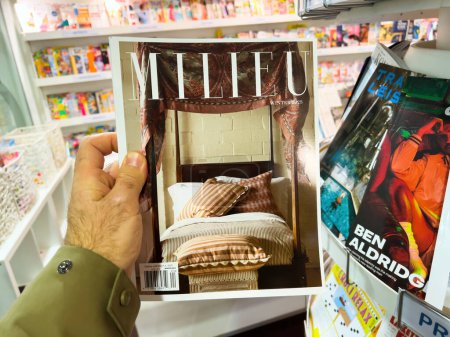 Téléchargez les photos : Londres, Royaume-Uni - 21 avril 2023 : une main d'homme récupère le dernier numéro du magazine Milieu dans un kiosque à journaux, mettant en vedette des meubles de lit luxueux sur sa couverture - en image libre de droit