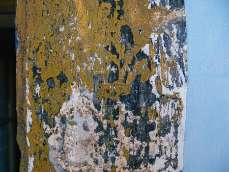 Téléchargez les photos : Le rebord de fenêtre d'une maison âgée porte les traces du temps, révélant plusieurs couches de peinture, passant d'une teinte bleu profond à un jaune chaud et ensoleillé sur la façade altérée - en image libre de droit