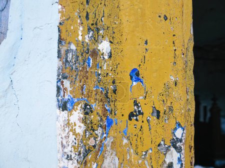 Téléchargez les photos : Le rebord de fenêtre d'une ancienne demeure met en valeur sa riche histoire à travers des couches de peinture, passant d'un bleu vif à un jaune accueillant sur la façade portée par le temps - en image libre de droit