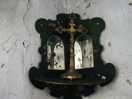 Téléchargez les photos : Un coin de prière dans une demeure abandonnée arbore deux miroirs ornés chacun d'une image de Jésus sur une croix métallique - en image libre de droit