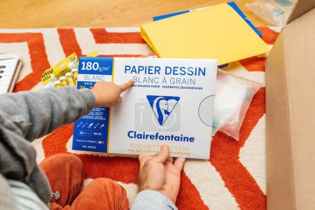 Foto de París, Francia - 1 de septiembre de 2023: Una mano de niños pequeños señala orgullosamente a Papier Blanc fabricado por Clairefontaine, lo que significa preparación para la escuela - Imagen libre de derechos