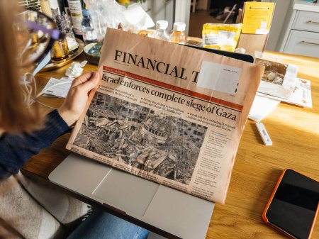 Photo for Paris, France - Oct 10, 2023: In a serene living room setting, a woman is captivated by the latest Financial Times newspaper with the headline Israel at War After Deadly Hamas Attack - Royalty Free Image