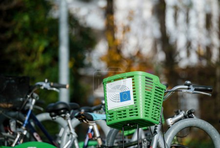 Foto de Estrasburgo, Francia - 22 de noviembre de 2022: Una bicicleta con una cesta se sienta al aire libre entre las plantas con el logotipo de insignia del Parlamento Europeo. Esta forma verde de transporte es perfecta para la carretera de Estrasburgo - Imagen libre de derechos