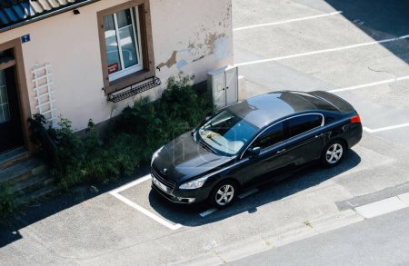 Téléchargez les photos : Graufthal, France - 26 mai 2023 : Une photo aérienne montrant une Peugeot noire élégante garée devant un bâtiment moderne - en image libre de droit