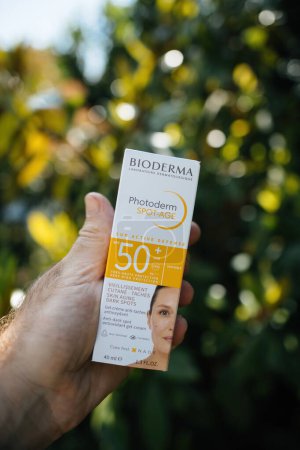 Photo for Paris, France - May 30, 2023: Male hand exhibits holds in garden package of Bioderma Photoderm Spot-Age Sun Defense 50 SPF cream for skin aging and dark spots - Royalty Free Image