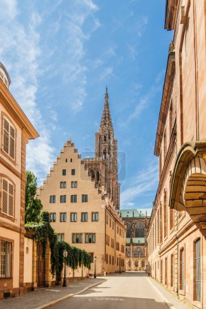 Foto de La majestuosa catedral de Notre Dame de Strasbourg se ve desde la Rue du Rohan, flanqueada por casas tradicionales alsacianas a ambos lados. - Imagen libre de derechos