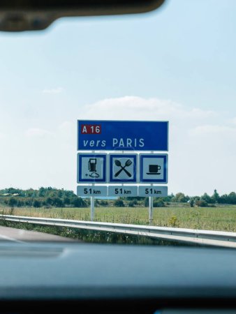Photo for Vers Paris sign on Frances A16 highway directs travelers toward Paris while indicating upcoming amenities like gas stations, restaurants, and coffee shops 80 km ahead - Royalty Free Image