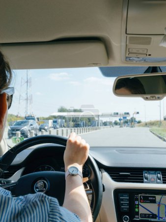 Téléchargez les photos : France - 17 août 2023 : De l'arrière, une femme stylée conduit un véhicule de luxe, en utilisant le guidage Apple Car à l'approche d'une zone de péage routier française - en image libre de droit