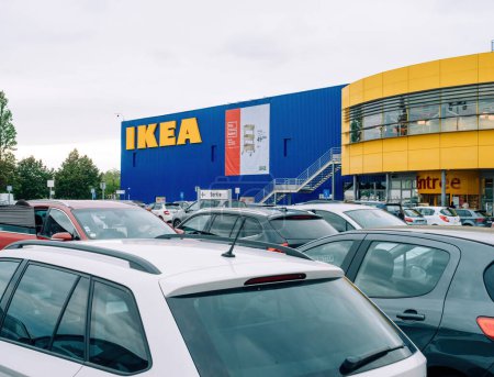 Foto de París, Francia - 31 / 08 / 2023: El gran logotipo de IKEA adorna la pared del centro comercial de muebles sueco, con coches bulliciosos en el estacionamiento - Imagen libre de derechos
