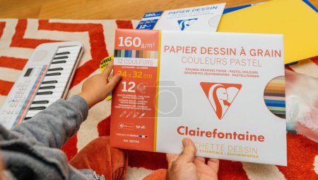 Photo for Paris, France - Sep 1, 2023: Father and son bonding while unboxing and inspecting various school items, including Clairefontaine drawing paper with a substantial 160-gram weight - Royalty Free Image
