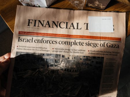 Téléchargez les photos : Paris, France - 10 oct. 2023 : La dernière édition du Financial Times est élégamment affichée sur un comptoir en bois, présentant le titre Israël en guerre après l'attaque meurtrière du Hamas - en image libre de droit