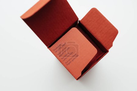 Photo for A vibrant red paper box with a focus on its environmentally friendly feature, showcasing text that indicates it is printed on recycled paper in multiple languages - Royalty Free Image