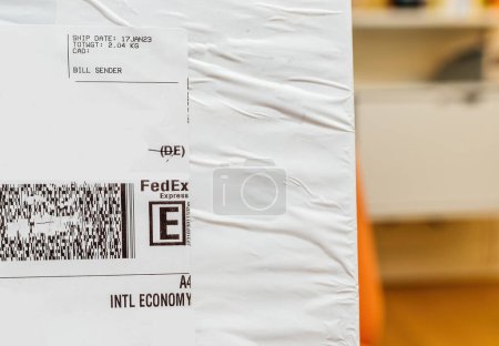 Foto de París, Francia - 23 de enero de 2023: Una macro toma de un paquete y sobre de FedEx, que simboliza los servicios de entrega urgente ofrecidos por la corporación global de mensajería. - Imagen libre de derechos