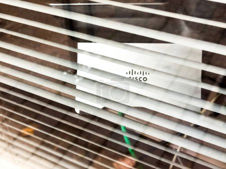 Foto de París, Francia - 25 de octubre de 2023: Una vista estéticamente capturada de un logotipo de los teléfonos Cisco VOIP dentro de una oficina contemporánea, sutilmente revelada a través de las lamas de persianas de las ventanas. - Imagen libre de derechos