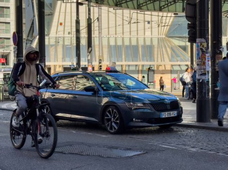 Foto de Estrasburgo, Francia - 1 de octubre de 2023: Una Skoda de lujo Estacionada en el centro de Estrasburgo, destacando la vida urbana. Un mensajero de reparto pasa rápidamente en bicicleta por el coche, haciendo hincapié en el movimiento de la ciudad - Imagen libre de derechos