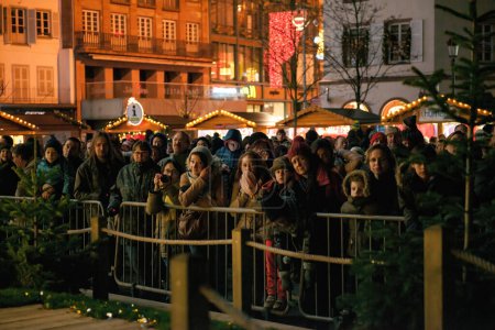Téléchargez les photos : Strasbourg, France - 28 nov. 2014 : Une foule de personnes, d'appareils photo et de smartphones en main, sirotant du vin chaud alors qu'ils anticipent avec impatience l'allumage officiel du sapin de Noël - en image libre de droit