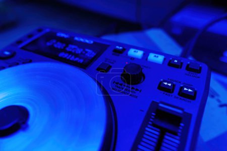 Téléchargez les photos : Un nouveau contrôleur de pont mélangeur DJ professionnel doté d'une coulée de couleur bleue, mettant l'accent sur ses fonctions de recherche de piste et de boucle - en image libre de droit