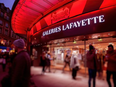 Photo for STRASBOURG, FRANCE - DEC 23, 2018: red color cast over Customers shopping in the winter evening a few days before Christmas in France at galleries Lafayette in central Strasbourg - Royalty Free Image
