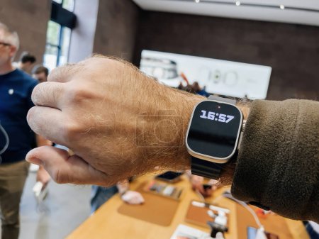Téléchargez les photos : Paris, France - 23 sept. 2023 : Une main masculine présente la nouvelle Apple Watch Ultra 2 en titane à l'Apple Store dès son premier jour de vente, avec un fond déconcentré de clients avides - en image libre de droit