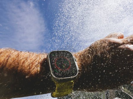 Foto de París, Francia - 27-sep-2023: Salpicando agua sobre el último Apple Watch Ultra 2 mientras se prueba en una piscina, con un cielo despejado en el fondo, mostrando sus capacidades resistentes al agua - Imagen libre de derechos
