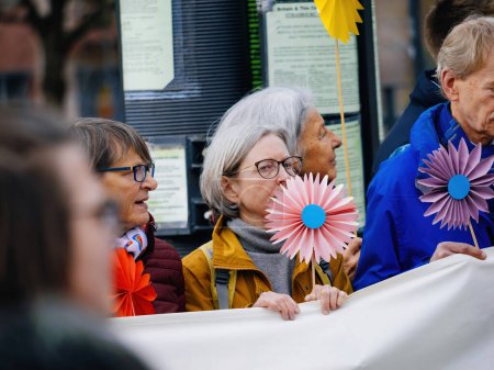Téléchargez les photos : Strasbourg, France - 29 mars 2023 : Des personnes âgées suisses se rassemblent devant la Cour européenne des droits de l'homme, portant des pancartes et des fleurs en papier, exigeant une action contre le changement climatique - en image libre de droit