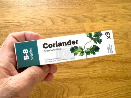Photo for Paris, France - Sep 28, 2023: a hand holding a packet of coriander seeds, with the label clearly displaying the plants name, Coriandrum sativum, and a growth timeline of 5-8 weeks, set against a - Royalty Free Image