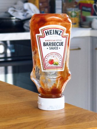 Foto de París, Francia - 29-sep-2023: Una botella vacía de salsa de barbacoa Heinz se sienta en un mostrador de madera, agregando un toque de cultura culinaria moderna al ambiente de las cocinas. - Imagen libre de derechos