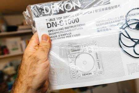 Photo for Paris, France - Oct 24, 2023: a male hand holds the instruction manual for the new Denon Professional DN-S1000 DJ mixing deck - Royalty Free Image