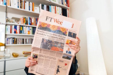 Photo for Paris, France - Oct 3, 2023: A woman engrossed in the latest FT Weekend edition, with a headline discussing Israels decision to cut Gaza links after the war in pursuit of a new security reality - Royalty Free Image