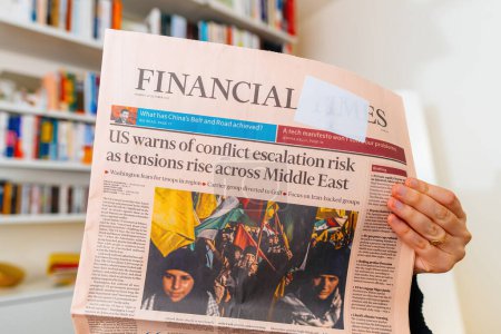 Photo for Paris, France - Oct 3, 2023: A woman engrossed in the latest Financial Times with a headline warning of conflict escalation risk amid rising tensions across the Middle East, particularly due to the - Royalty Free Image